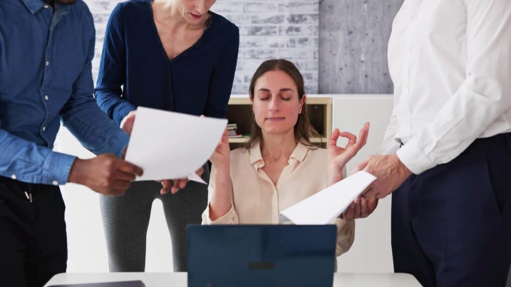 woman at a desk with people around her