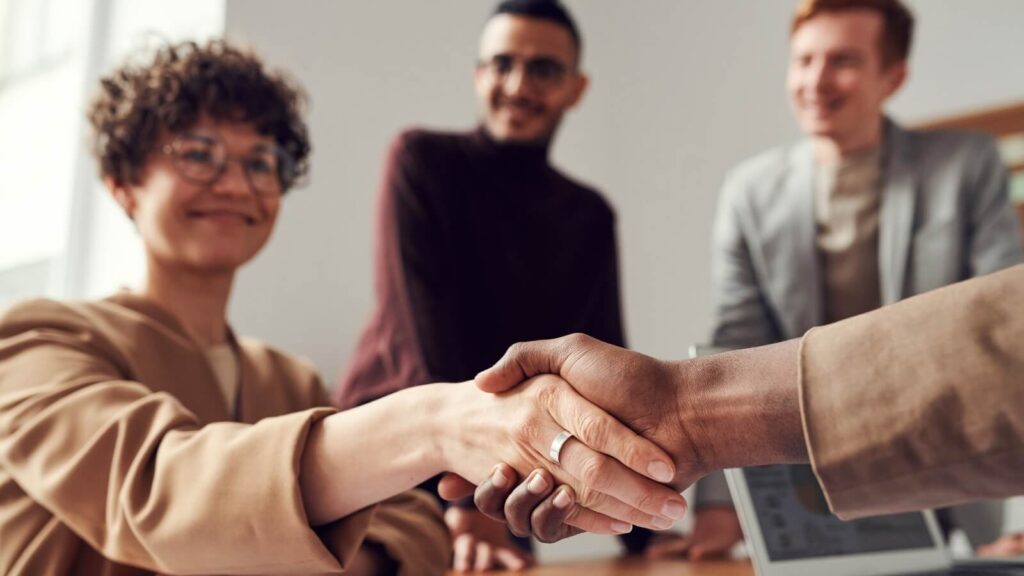 woman shaking hands with someone and two people in the background