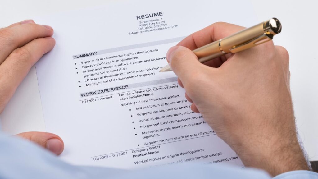 a closeup of a hand writing on a resume