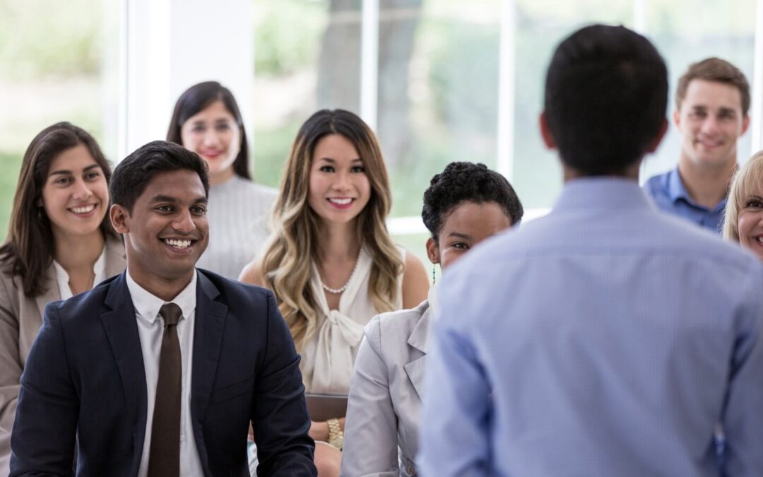 Crowd of employees smiling at a man leading a meeting