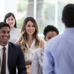 Crowd of employees smiling at a man leading a meeting