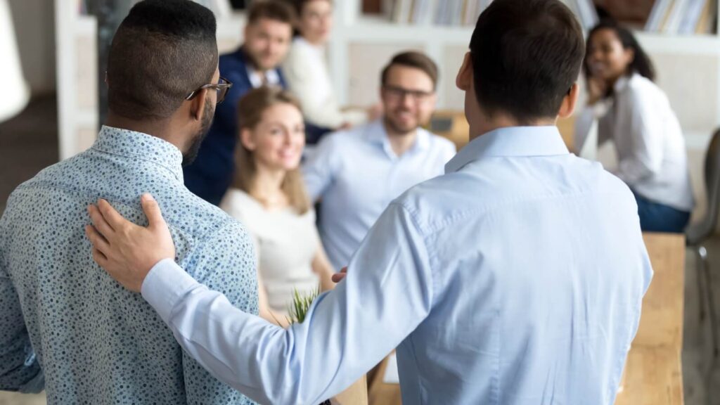 Two men in front of crowd in a meeting